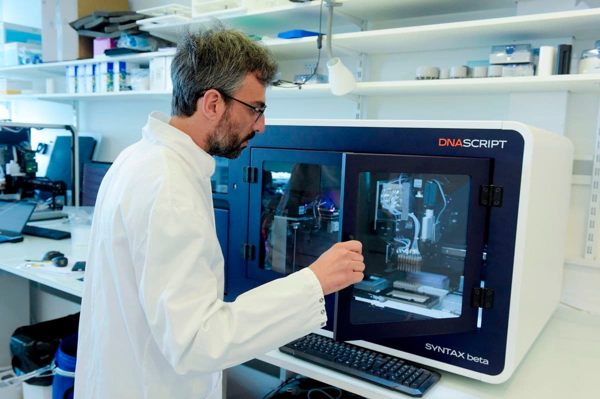 Un homme en blouse de laboratoire manipule du matériel de laboratoire. Il se trouve dans un laboratoire avec des étagères remplies de fournitures et d'équipement scientifique en arrière-plan.